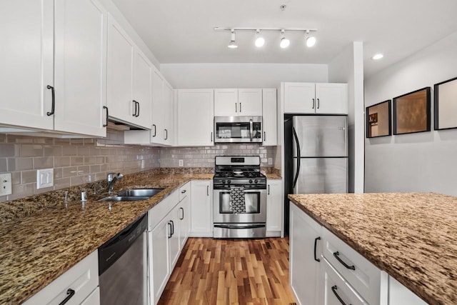 kitchen with light wood-style flooring, a sink, white cabinets, appliances with stainless steel finishes, and backsplash