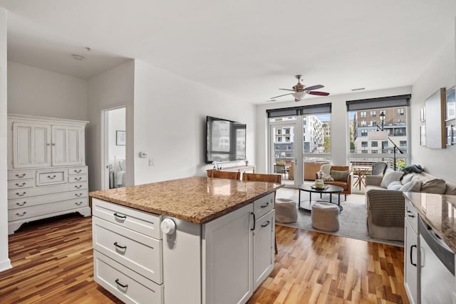 kitchen featuring light stone counters, light wood-type flooring, a center island, and white cabinets