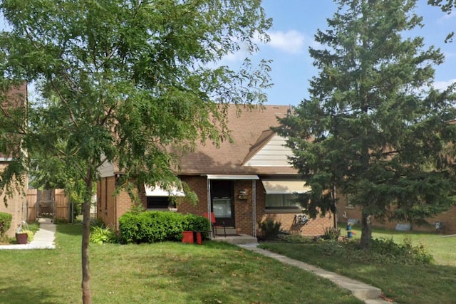 view of front of house with brick siding, a front lawn, and fence