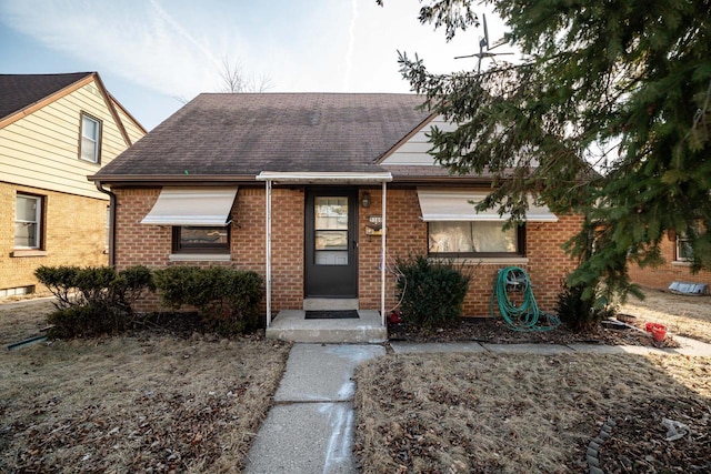 view of front of house featuring brick siding and roof with shingles