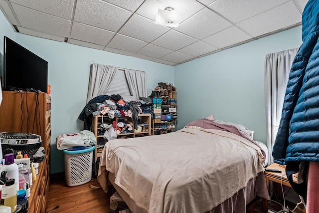 bedroom with a drop ceiling and wood finished floors