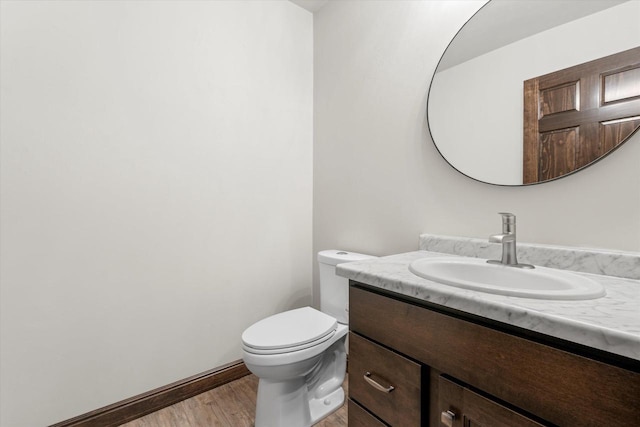 bathroom with vanity, wood finished floors, toilet, and baseboards