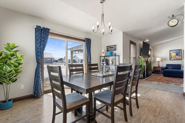 dining space with light wood-type flooring, baseboards, vaulted ceiling, and a chandelier