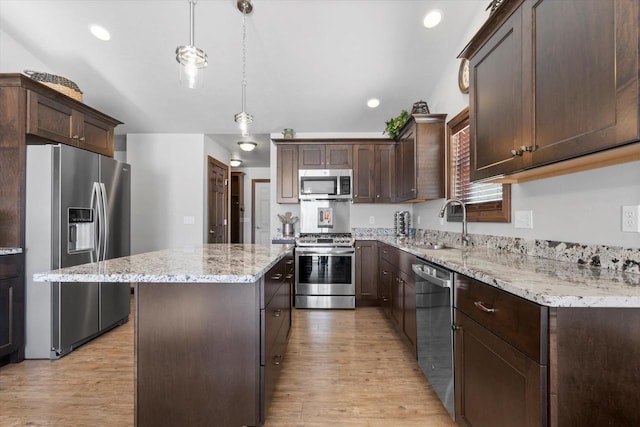 kitchen featuring light wood-type flooring, dark brown cabinetry, appliances with stainless steel finishes, and a center island