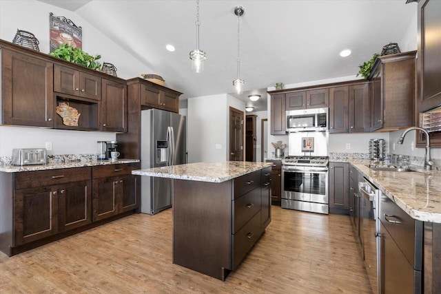 kitchen featuring light wood-style flooring, appliances with stainless steel finishes, a sink, dark brown cabinetry, and a kitchen island