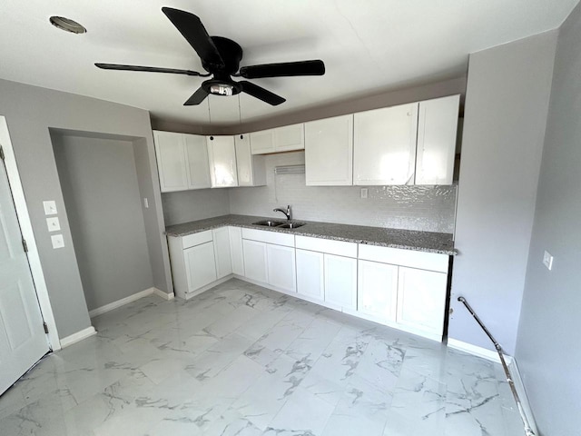 kitchen featuring white cabinetry, baseboards, marble finish floor, and a sink