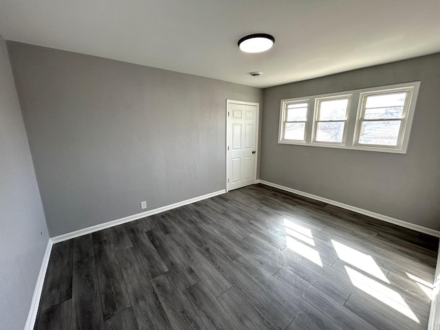 empty room with baseboards and dark wood-style flooring