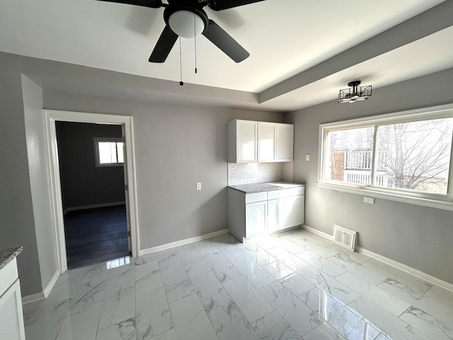 kitchen with visible vents, baseboards, marble finish floor, and white cabinets