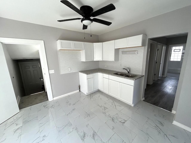 kitchen featuring ceiling fan, white cabinets, marble finish floor, and a sink