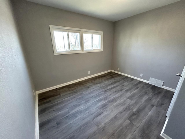 unfurnished room with dark wood-type flooring, baseboards, and visible vents