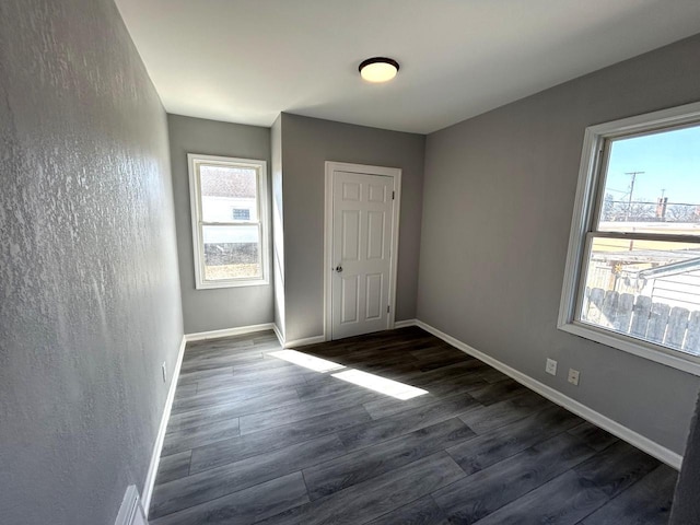 unfurnished bedroom with baseboards and dark wood-style flooring