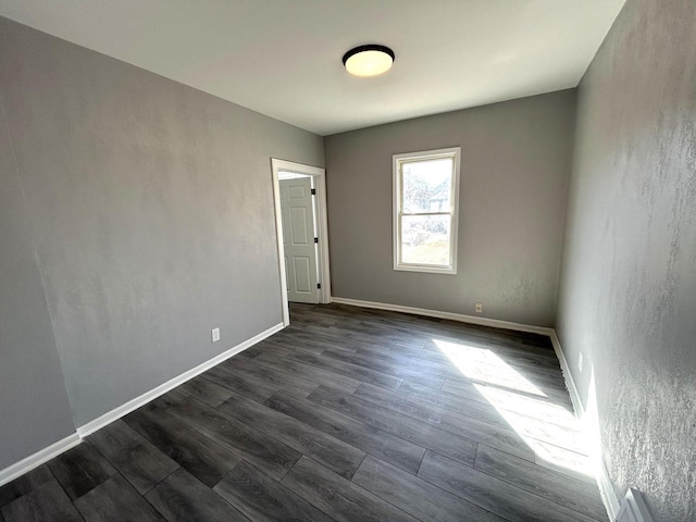 spare room with dark wood-style floors and baseboards