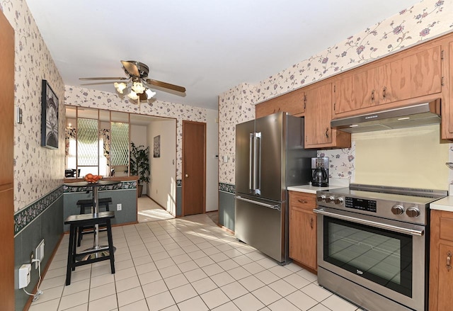 kitchen with wallpapered walls, light countertops, under cabinet range hood, and stainless steel appliances