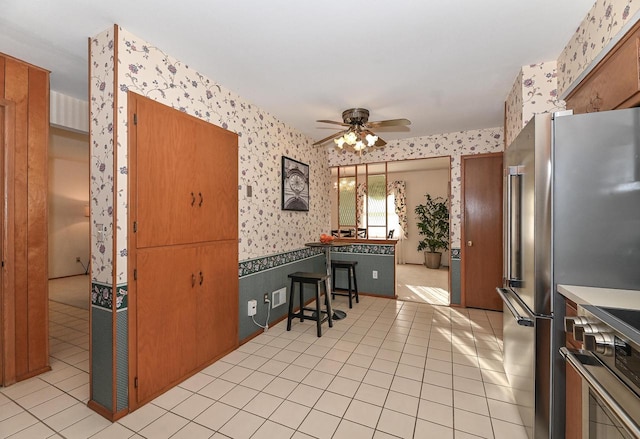 kitchen with wallpapered walls, ceiling fan, wainscoting, range, and high end refrigerator