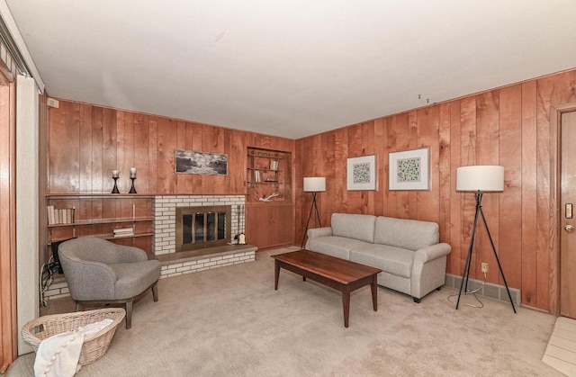 living room with wooden walls, carpet flooring, a brick fireplace, and visible vents