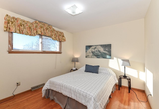 bedroom featuring wood finished floors, visible vents, and baseboards