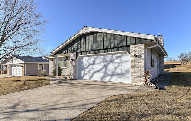 view of front facade featuring an attached garage, brick siding, a chimney, concrete driveway, and board and batten siding