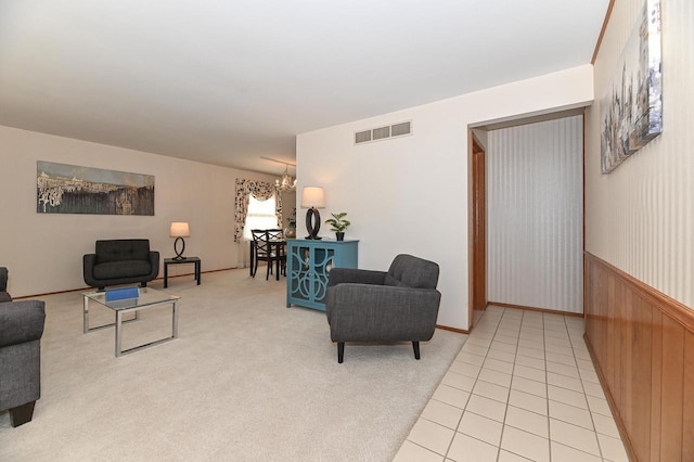 living area featuring visible vents, light tile patterned flooring, wainscoting, light carpet, and a chandelier