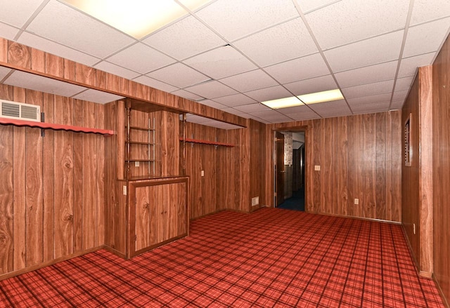 finished below grade area featuring visible vents, wood walls, and carpet