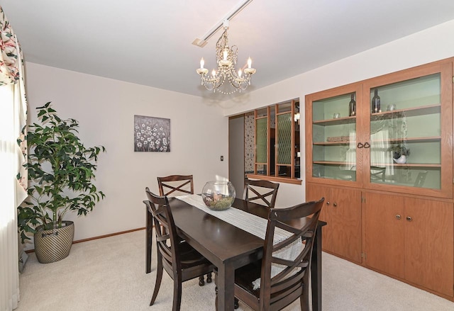 dining room with a notable chandelier, light colored carpet, and baseboards