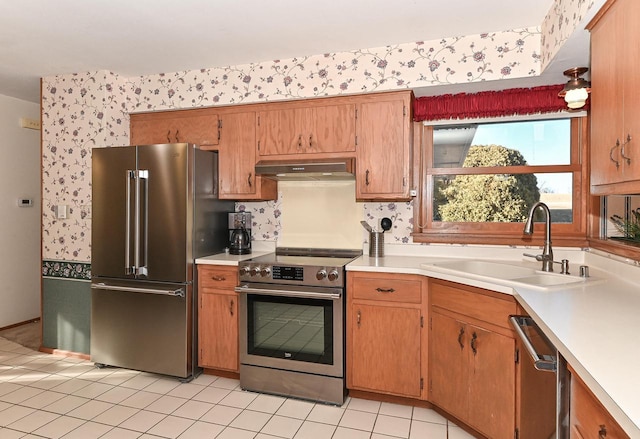 kitchen featuring under cabinet range hood, appliances with stainless steel finishes, light countertops, and a sink