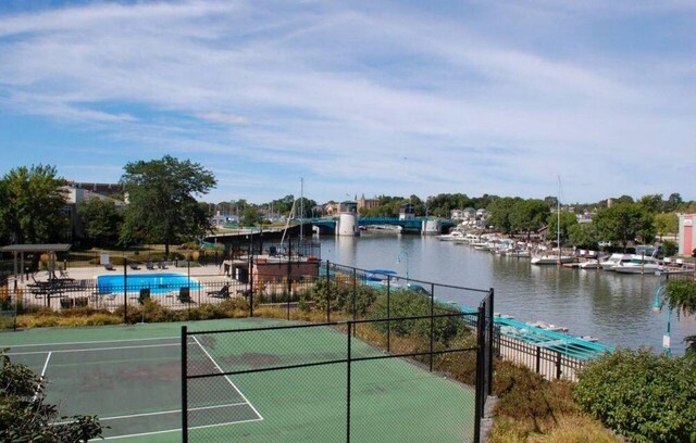 view of sport court featuring fence and a water view