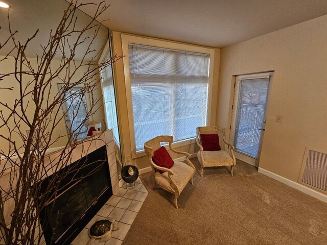 living area featuring visible vents, carpet flooring, a tile fireplace, and baseboards