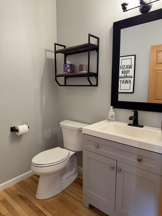 bathroom with baseboards, toilet, wood finished floors, and vanity