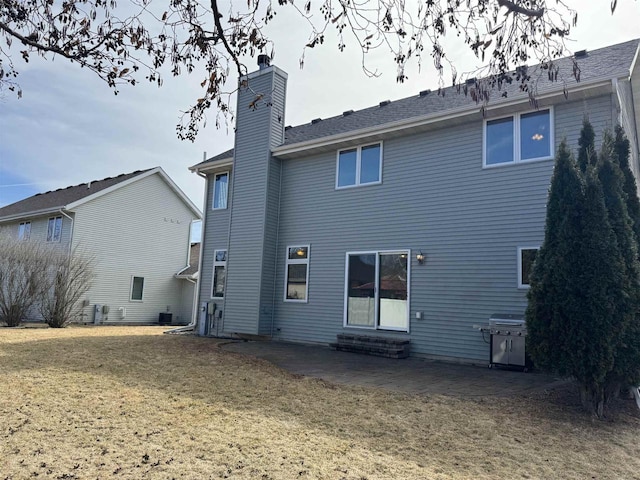 back of property with a yard, a patio, a chimney, and entry steps