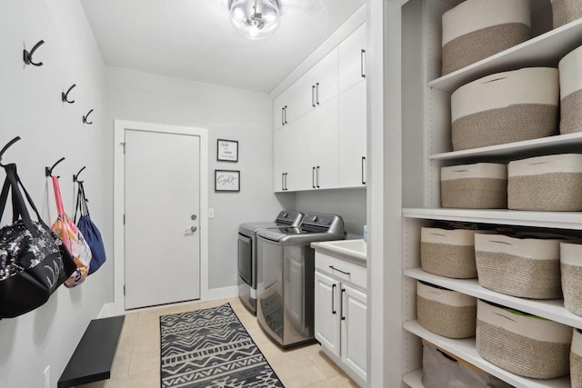 laundry room featuring cabinet space, light tile patterned floors, washing machine and dryer, and baseboards