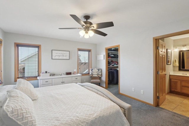 bedroom featuring baseboards, a sink, a spacious closet, a closet, and light carpet