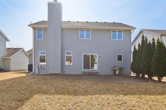 back of house with a yard, a patio area, central AC, and a chimney