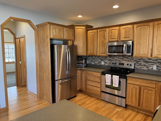 kitchen featuring tasteful backsplash, dark countertops, recessed lighting, light wood-style flooring, and appliances with stainless steel finishes