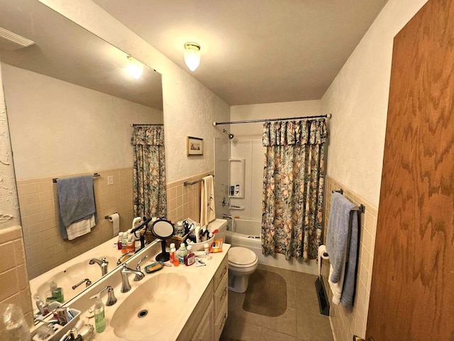 full bath featuring tile patterned flooring, wainscoting, tile walls, and toilet