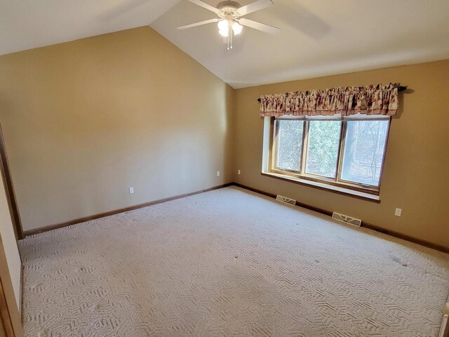 carpeted spare room featuring lofted ceiling, baseboards, and visible vents