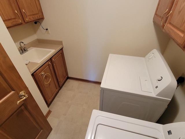 laundry room featuring light floors, cabinet space, a sink, washer / dryer, and baseboards