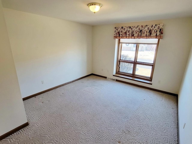 empty room with light colored carpet, visible vents, and baseboards