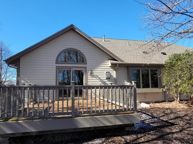 back of property with a deck and roof with shingles