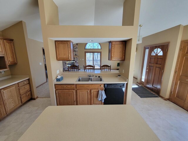 kitchen featuring brown cabinetry, black dishwasher, light countertops, and a sink