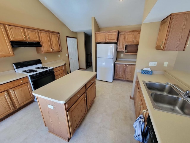 kitchen featuring range with gas stovetop, light floors, freestanding refrigerator, a sink, and under cabinet range hood