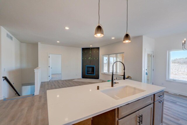 kitchen featuring a fireplace, light countertops, a sink, and decorative light fixtures