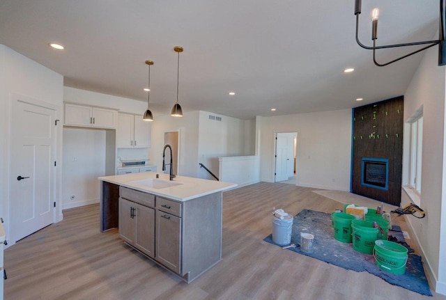 kitchen with light wood-type flooring, a fireplace, a sink, and recessed lighting