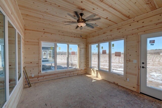 unfurnished sunroom featuring a ceiling fan, wooden ceiling, and a healthy amount of sunlight