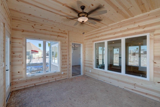 unfurnished room featuring a sunroom, wood walls, wood ceiling, and a ceiling fan