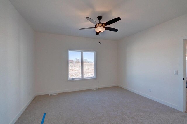 spare room with baseboards, a ceiling fan, visible vents, and light colored carpet