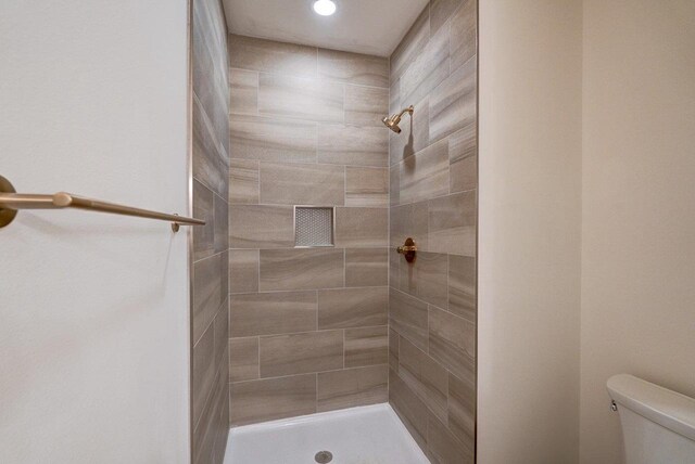 bathroom featuring a tile shower and toilet