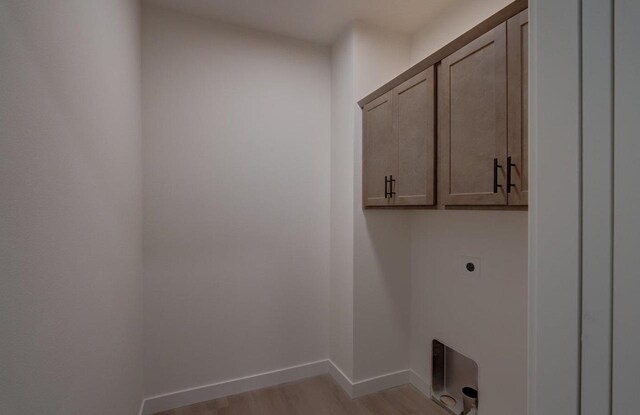 laundry room featuring light wood-style floors, hookup for an electric dryer, cabinet space, and baseboards