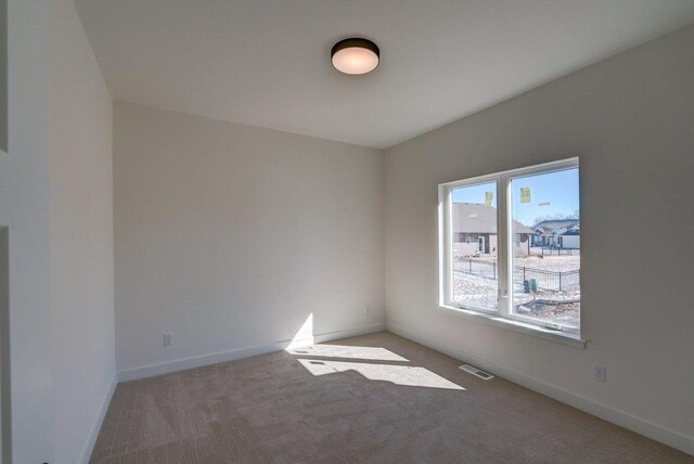 unfurnished room with visible vents, light carpet, and baseboards