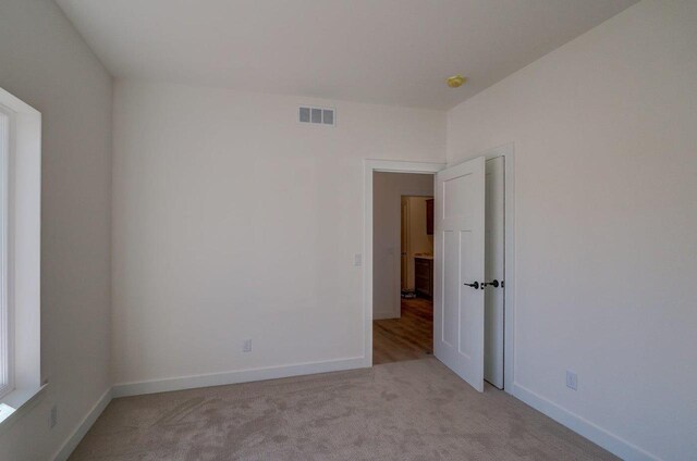 carpeted empty room featuring visible vents and baseboards