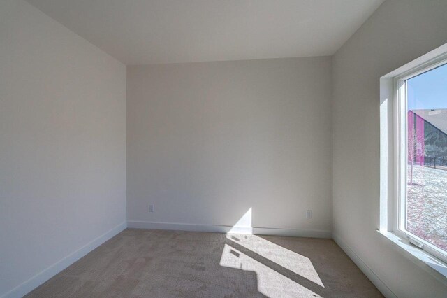 unfurnished room with light carpet and baseboards